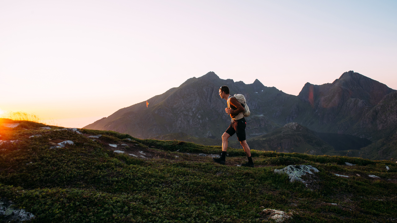 Man running up a hill in Norway at sunset.