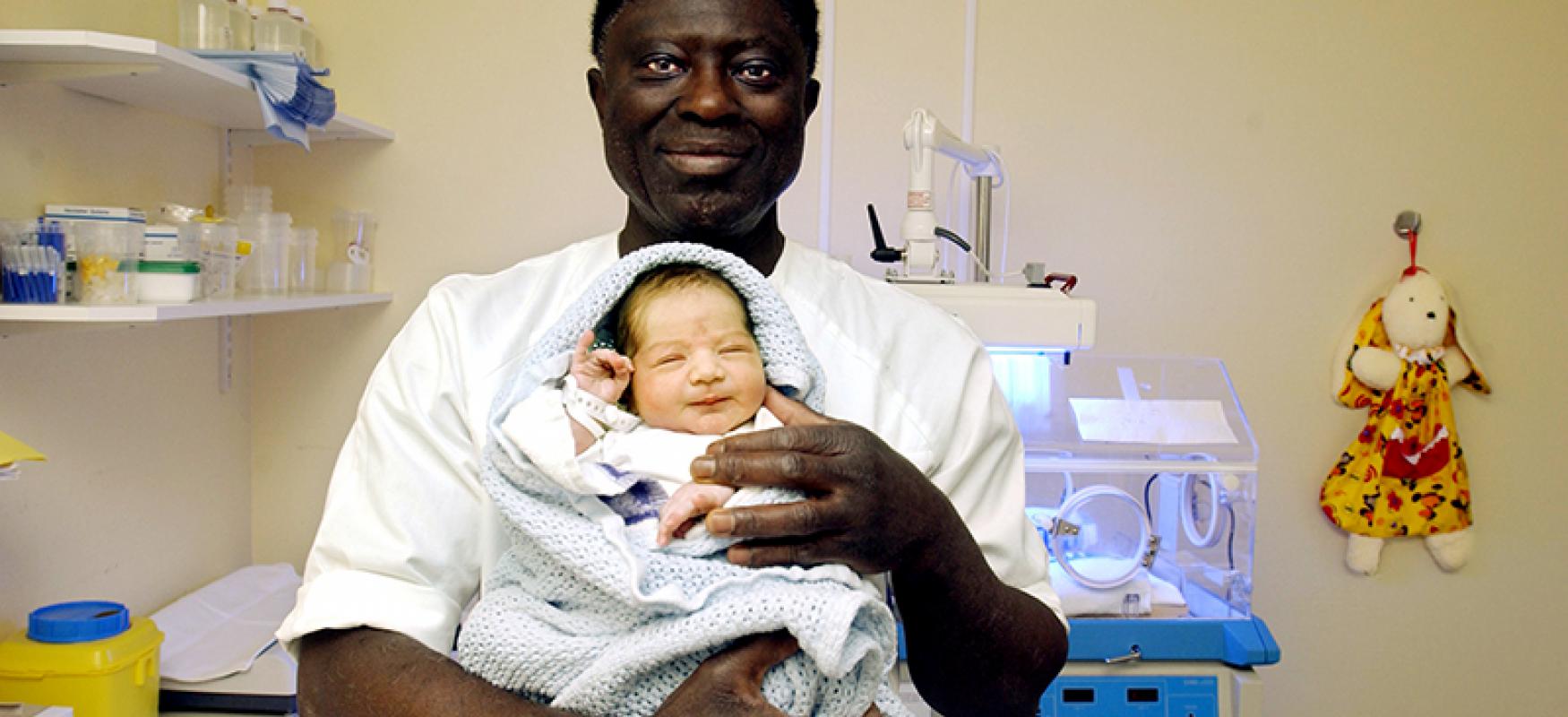 Nurse holding a newborn baby at a hospital.