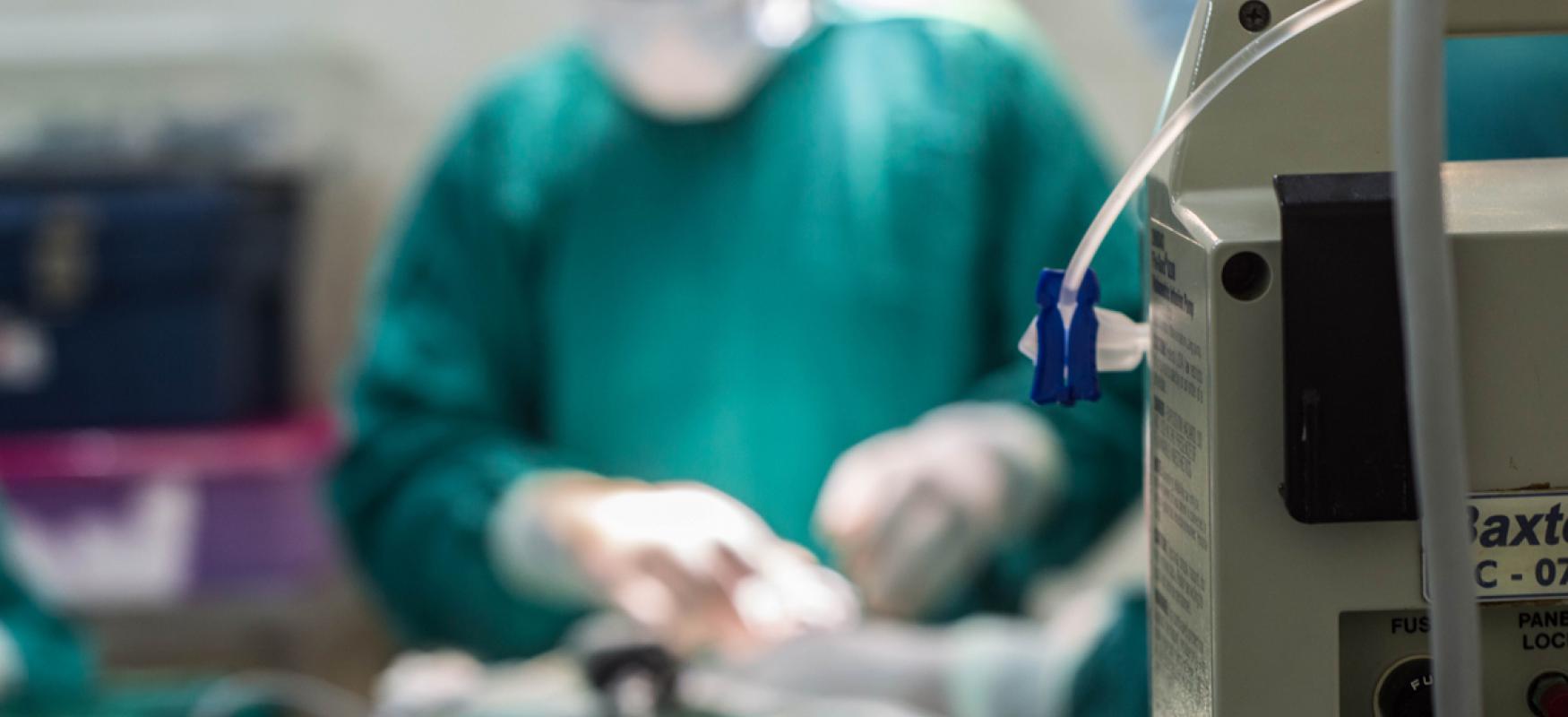 Close-up of a medical device with a doctor treating a patient blurred in the background.