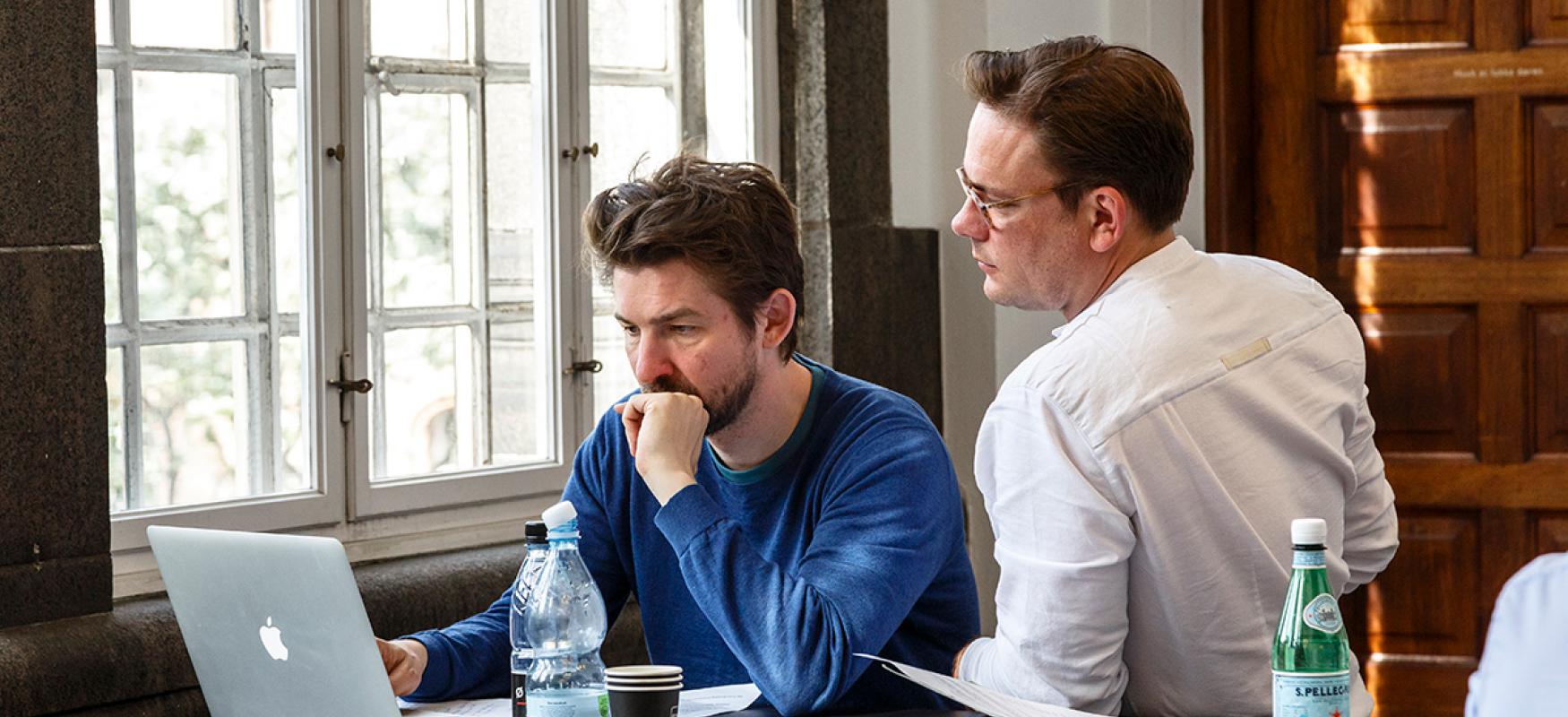 Two men working in front of a laptop in an office.