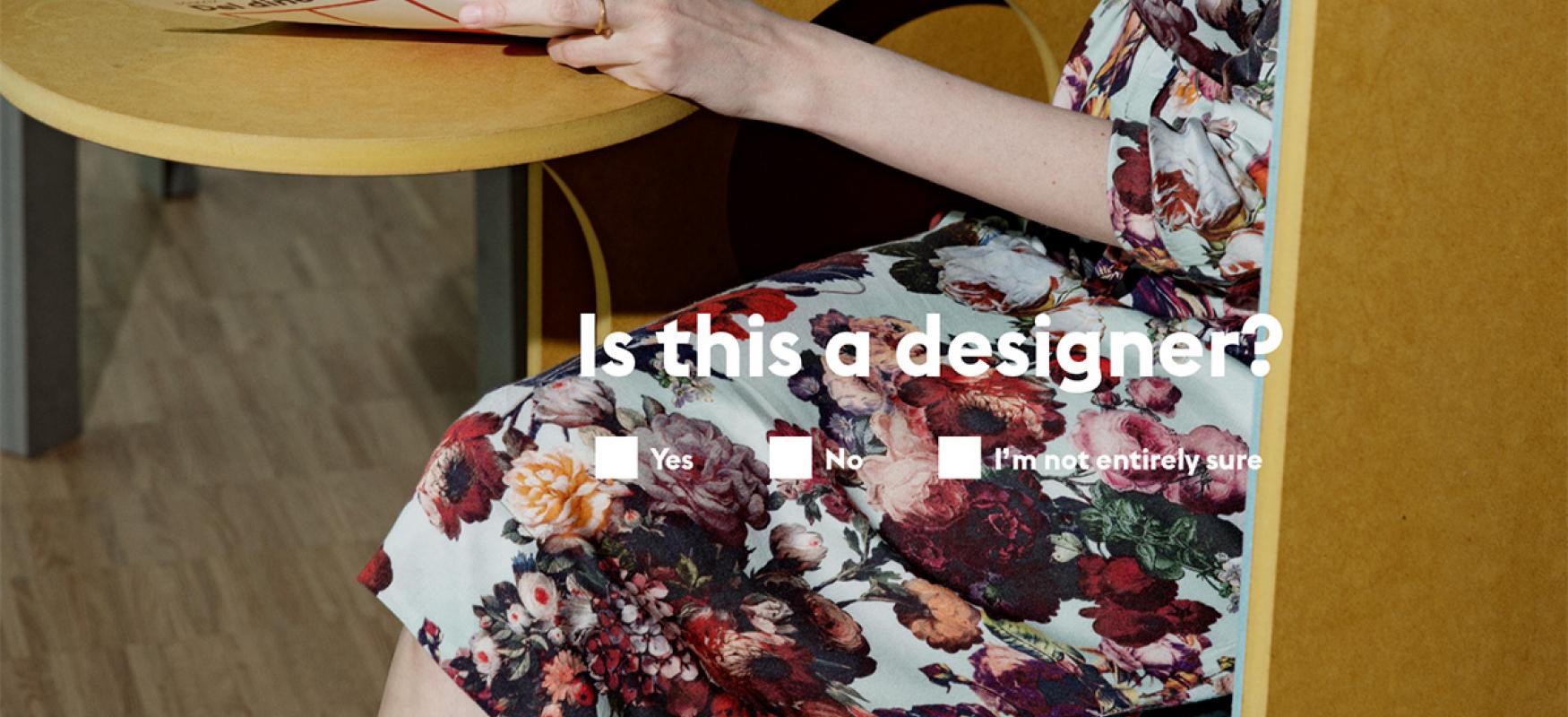 A woman in a flower dress sitting at a cafe table with the text "is this a designer"?