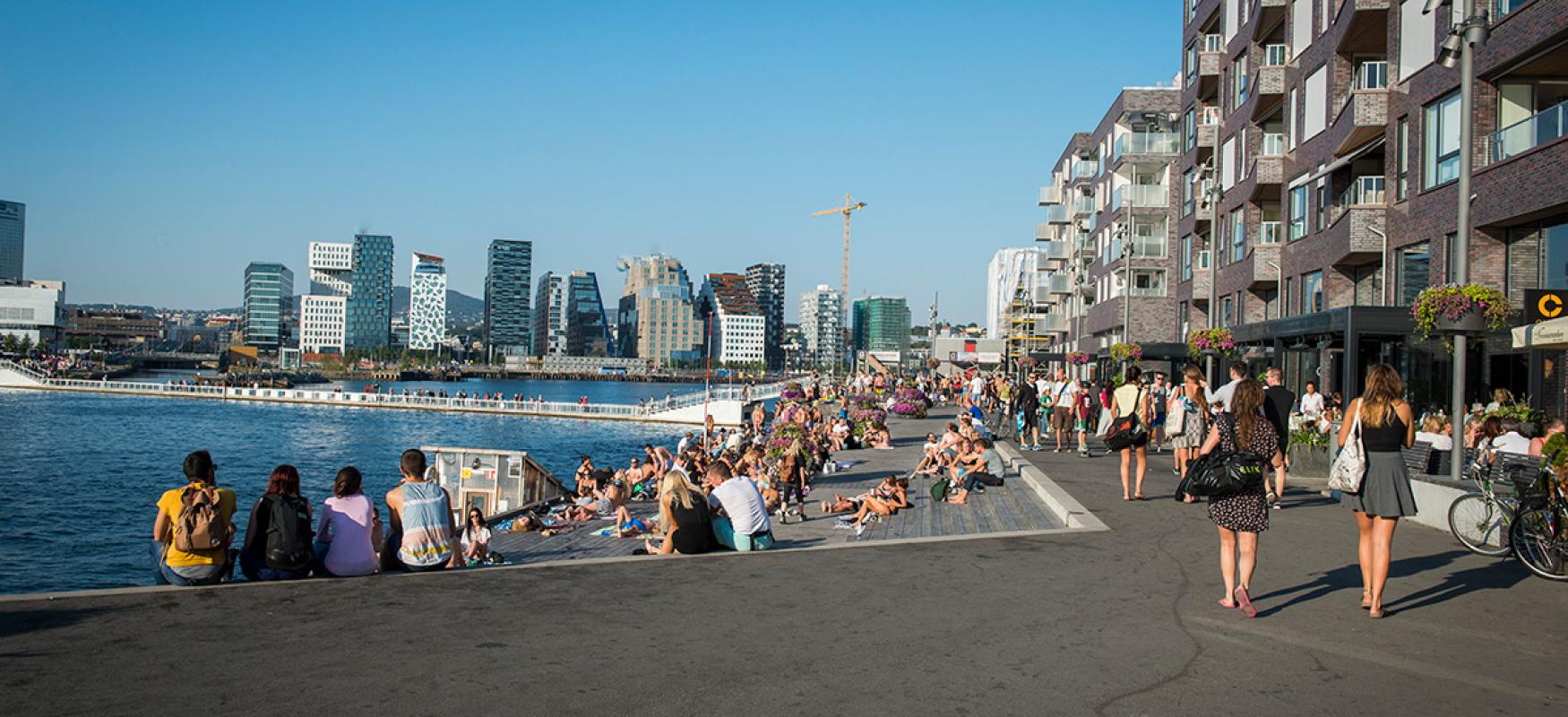 People sitting by the waterfront on a summers day at Sørenga in Oslo.