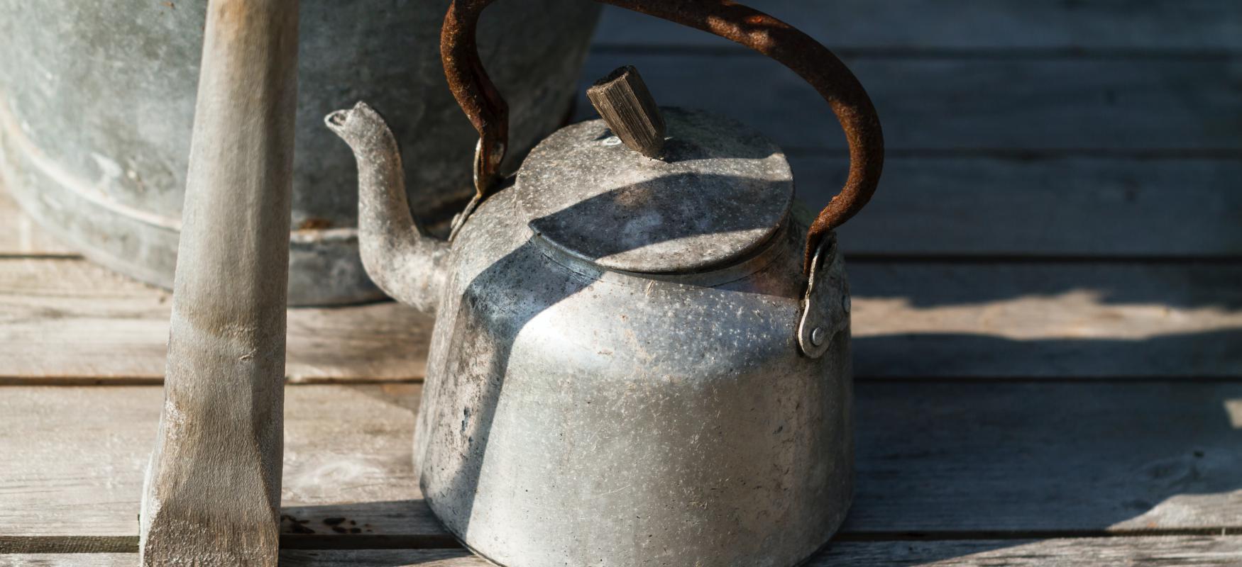 kettle standing outside on wooden shelf.