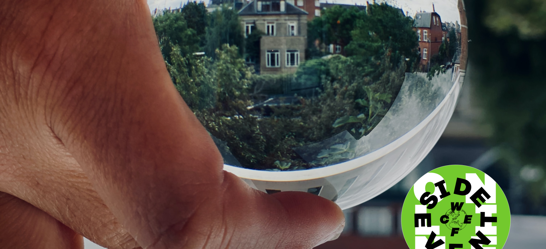 Person holding glass globe with reflecting building and trees in the background. WCEFonline sideevent logo