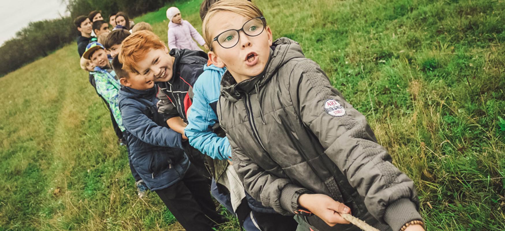 Children in a field playing tug of war