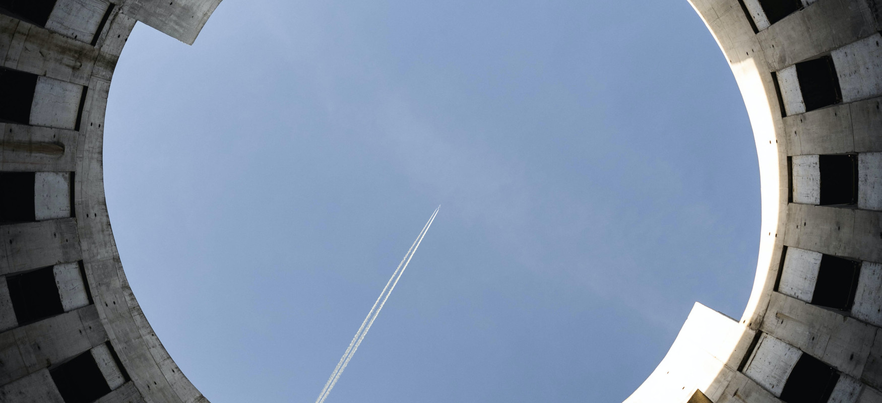 Looking up a round conctrete construction and seeing a plane flying over