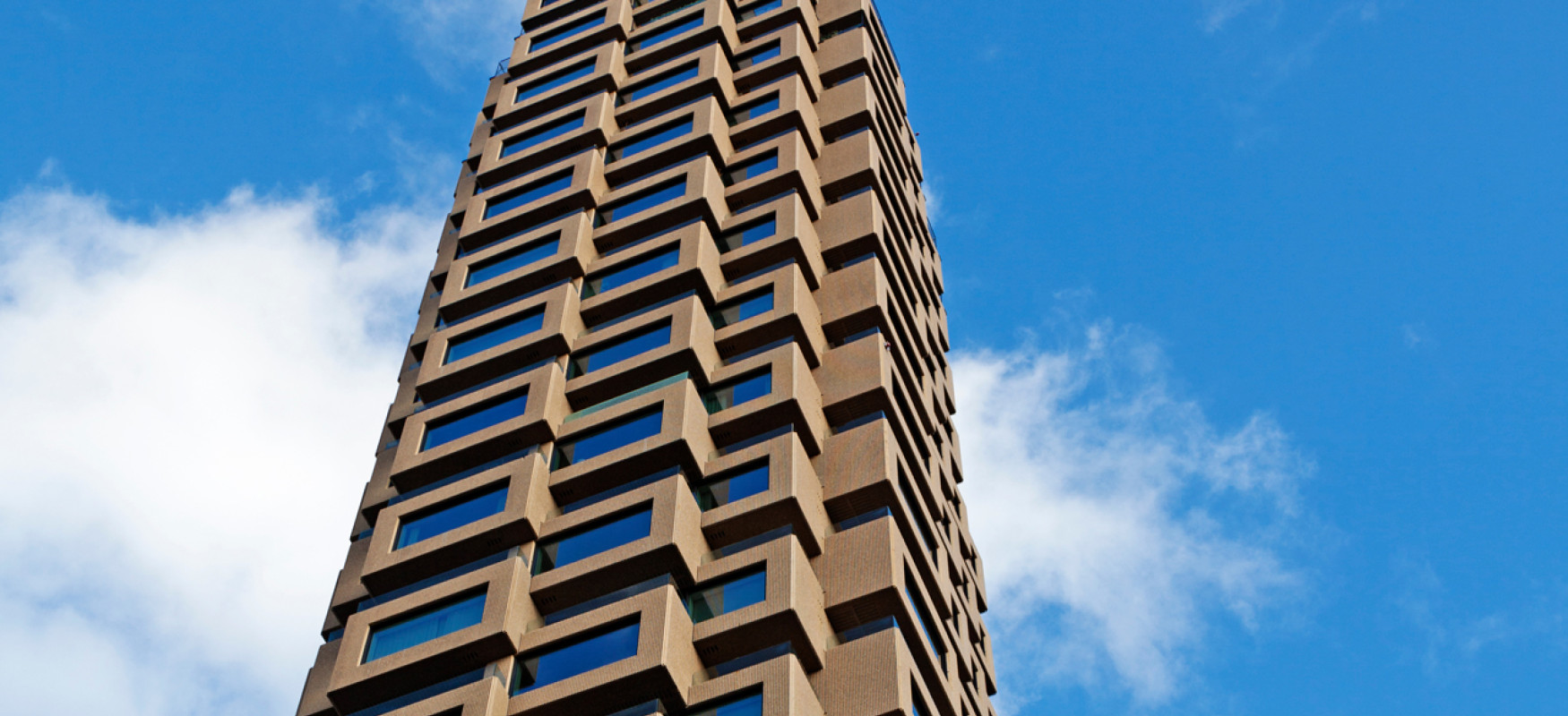 Picture of a high rise building seen from the street and stretching towards the sky