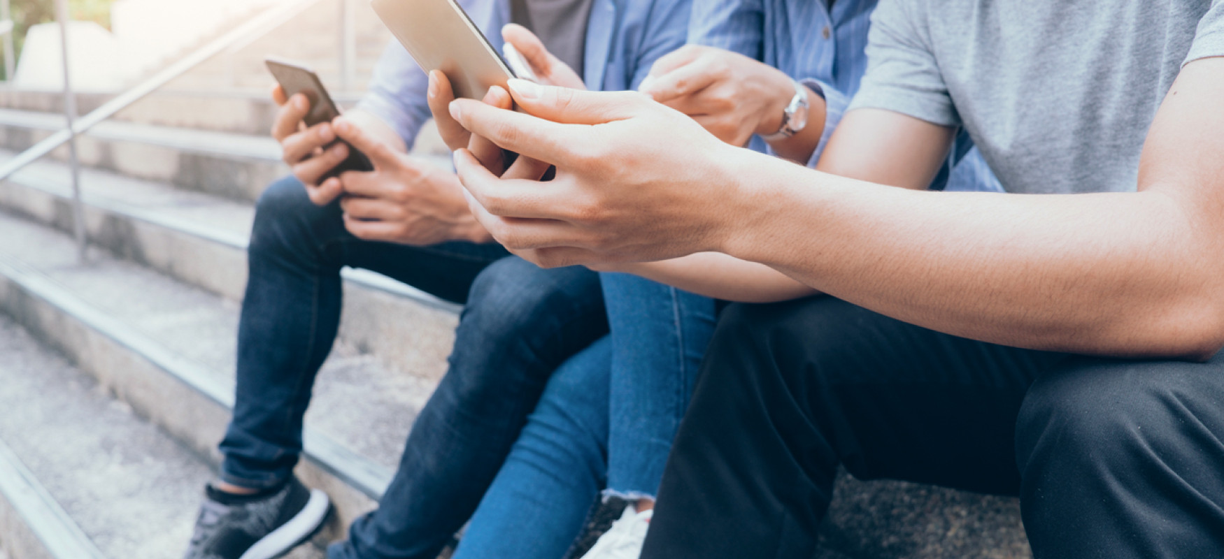 Three persons sitting on the stair playing with their mobile phones