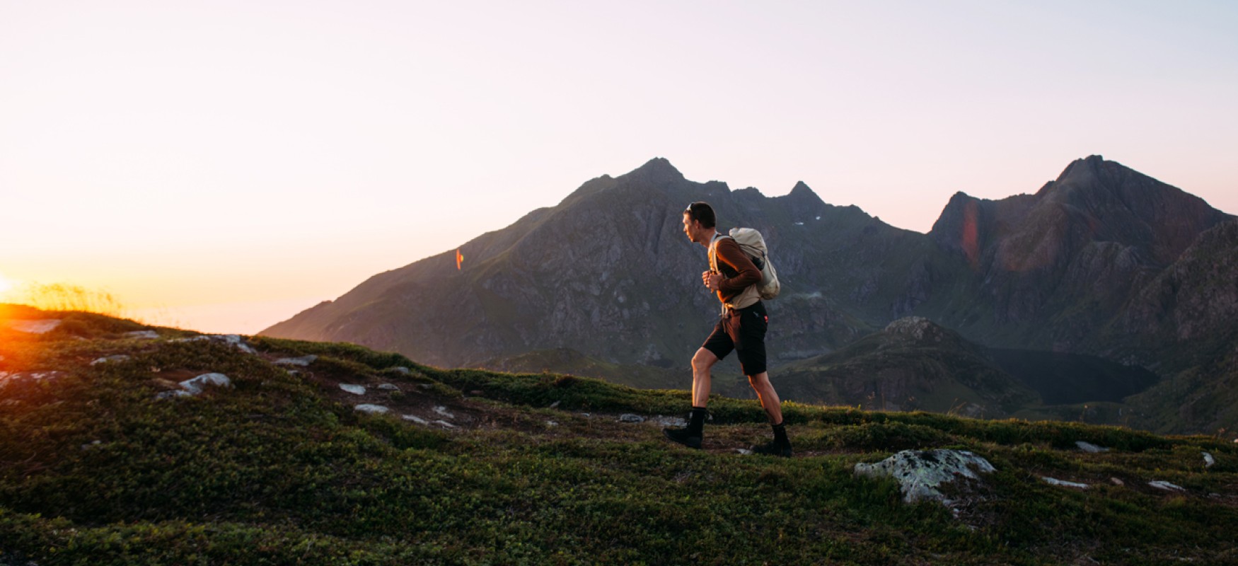 Man running up a hill in Norway at sunset.