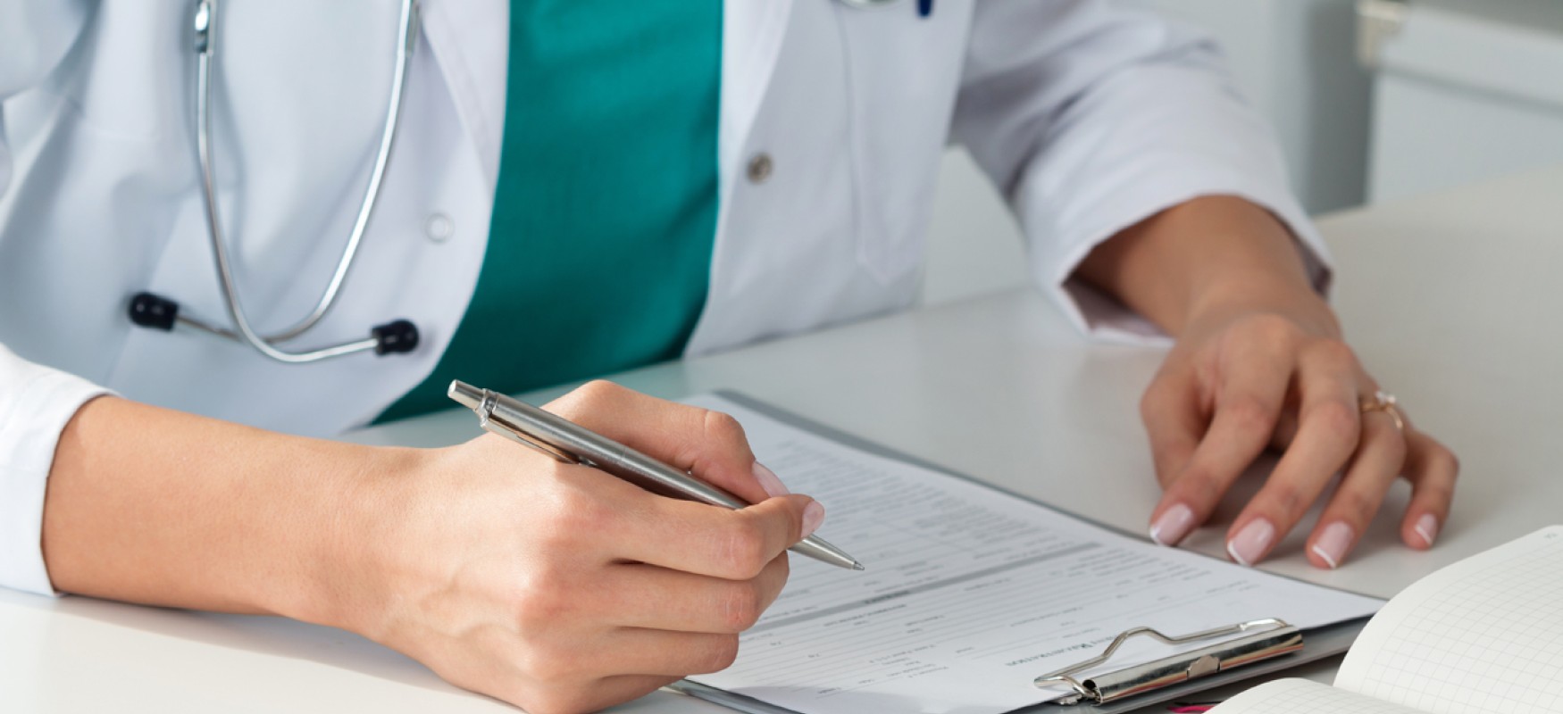 Medical personel writing with pen and paper at a desk