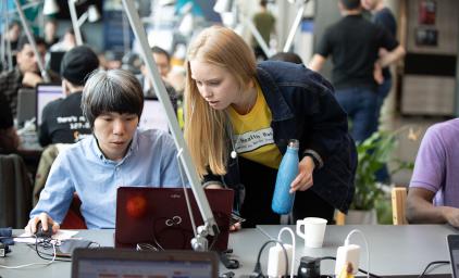 Two people in front of a laptop at a hackathon in Helsinki.