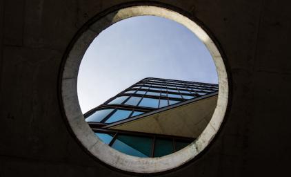 Building in Copenhagen seen through a circular hole in a concrete wall.