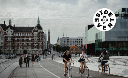 Two women driving their bikes across a bridge in Copenhagen.