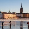 Five person ice skating frozen Riddarfjärden bay by Gamla Stan island, on a sunny winter day in Stockholm