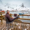 Man sitting on a chair on the dock in Lofoten working on a computer