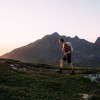 Man running up a hill in Norway at sunset.